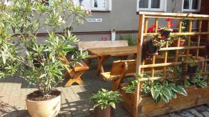 a wooden table and bench with potted plants on a patio at Hotelik w Centrum in Toruń