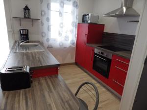 uma pequena cozinha com armários vermelhos e um fogão em TY KASTELL PAOL em Saint-Pol-de-Léon