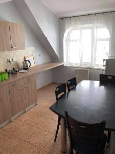 a kitchen with a black table and chairs and a table and a window at Apartamenty nad jeziorem - 4 in Ełk