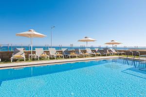 a swimming pool with chairs and umbrellas and the ocean at Irida Villa in Rethymno Town