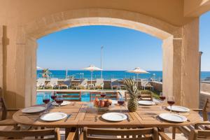 a table with wine glasses and a view of the ocean at Irida beachfront Villa for 12 steps to amenities in Rethymno