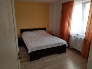 Un pequeño dormitorio con una cama con sábanas blancas y una ventana en Apartament 8 Central en Târgu Mureș