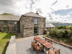 a stone house with a picnic table and benches at Cefn Gwyn in Talsarnau