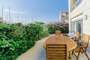 Marina Apartments by Olala Homes في حرزيليا بي: طاولة وكراسي خشبية على الفناء