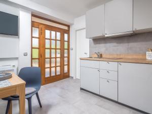 uma cozinha com armários brancos e uma mesa e cadeiras em Apartment Beni-1 by Interhome em Matulji