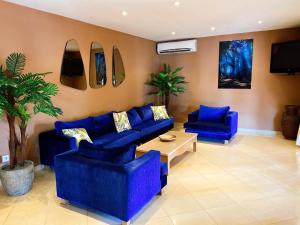 een woonkamer met blauwe banken en een tv bij Airport Hotel Casino du Cap-vert in Dakar
