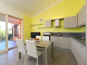 eine Küche mit einem Tisch und weißen Stühlen sowie eine Küche mit gelben Wänden in der Unterkunft Holiday Home Baia delle Mimose by Interhome in Valledoria