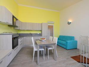 eine Küche mit einem Tisch und Stühlen sowie einem blauen Sofa in der Unterkunft Holiday Home Baia delle Mimose by Interhome in Valledoria