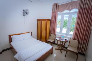 Un dormitorio con una cama y una mesa y una ventana. en Khách Sạn Sơn Hạ, en Kon Tum