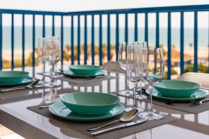a table with plates and wine glasses on a balcony at ApartUP Patacona Essence in Valencia
