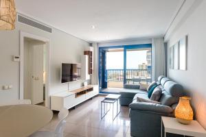 a living room with a blue couch and a television at ApartUP Patacona Essence in Valencia
