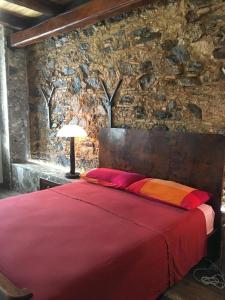 1 dormitorio con cama roja y pared de piedra en B&B Le Casette, en SantʼOnofrio