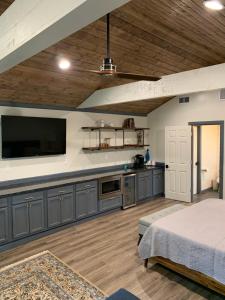 uma grande cozinha com armários azuis e uma televisão de ecrã plano em Salado Cottage Retreat near Downtown em Salado