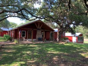 a red house with a tree in the yard at Salado Cottage Retreat near Downtown in Salado