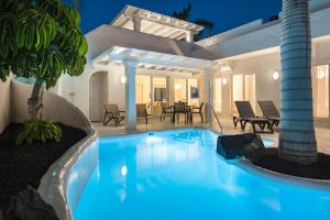 a swimming pool in a house with a palm tree at Bahiazul Villas Corralejo by Vreagestion in Corralejo
