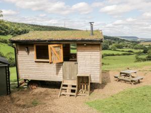 a small house with a grass roof with a bench and a table at Shepherd's Hut in Scarborough