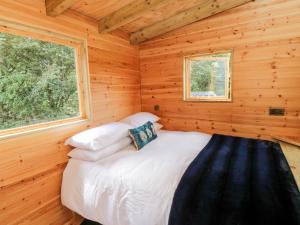 Ce lit se trouve dans une cabane en rondins dotée d'une fenêtre. dans l'établissement Shepherd's Hut, à Scarborough