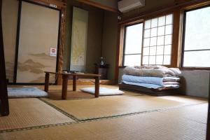 a room with a table and some windows and a rug at Minsyuku Koshiyama in Shirakawa