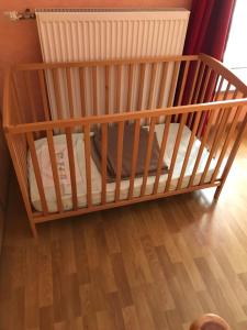 een houten wieg in een kamer met een houten vloer bij Aux 3 Loups in Châtenois