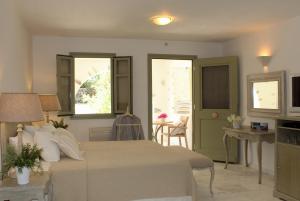 a bedroom with a bed and a table and windows at Saint Andrea Seaside Resort - Adults Only in Naousa