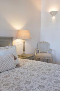 a bedroom with a bed with a lamp and a chair at Saint Andrea Seaside Resort - Adults Only in Naousa