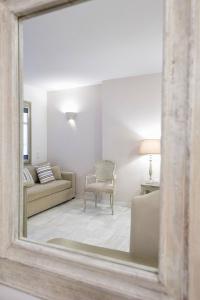 a mirror reflecting a living room with a couch and a chair at Saint Andrea Seaside Resort - Adults Only in Naousa