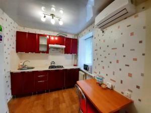 クラマトルスクにあるStusa Apartment Luxuryのキッチン(赤いキャビネット、木製テーブル付)