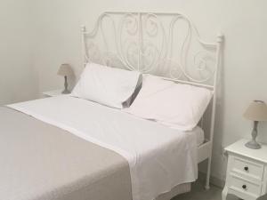 un letto bianco con testiera bianca e cuscini bianchi di Bed & Breakfast Piazza Matteotti a Stornara