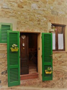 una casa con ventanas con persianas verdes y una puerta en Val d'Orcia nel Borgo, en Castiglione dʼOrcia