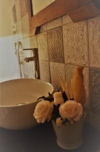 a white bowl and flowers on a counter next to a sink at Val d'Orcia nel Borgo in Castiglione dʼOrcia