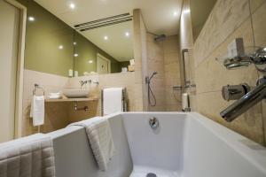 a bath tub sitting next to a sink in a bathroom at Hotel de France in Saint Helier Jersey