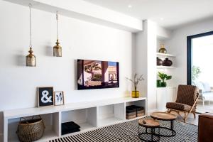una sala de estar blanca con TV en la pared en Luxe Apartments Hotel del Golf - Las Brisas Marbella en Marbella