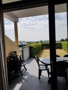 een patio met stoelen en een tafel en uitzicht op een veld bij Lac de Eau d Heure Appartement C1 Famille RANOCHA DUPREZ in Badon