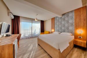 a bedroom with a large bed and a television at Sunset Hotel & Beach in Dobra Voda