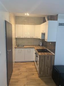 a kitchen with white cabinets and a wooden floor at Słoneczna in Miedzygorze