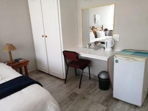 a bedroom with a desk and a bed and a mirror at Acorn Lodge & SKYDECK in Potchefstroom +93 photos