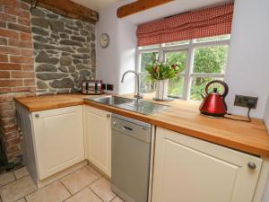a kitchen with a sink and a stone wall at Preacher's Cottage in Llanbadarn-fynydd