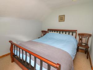 1 Schlafzimmer mit einem Bett und 2 Stühlen in der Unterkunft Preacher's Cottage in Llanbadarn-fynydd
