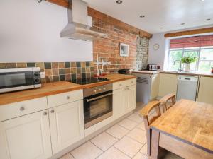 een keuken met witte kasten, een tafel en een magnetron bij Preacher's Cottage in Llanbadarn-fynydd +17 foto's