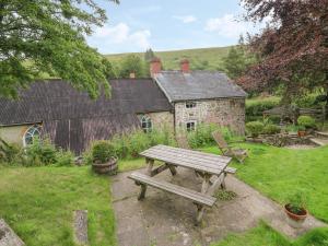 een houten picknicktafel in een tuin met een huis bij Preacher's Cottage in Llanbadarn-fynydd