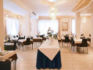 a dining room with tables and chairs and a chandelier at Hotel Abel & Residence in Cesenatico