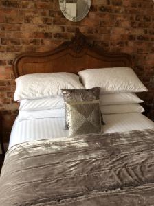 a bed with white sheets and pillows next to a brick wall at Holly Tree Cottage in High Etherley