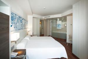 a bedroom with a large white bed and a bathroom at Port Benidorm Hotel & Spa 4* Sup in Benidorm