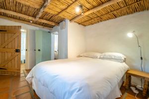 sypialnia z białym łóżkiem i drewnianym sufitem w obiekcie Natte Valleij w mieście Klapmuts