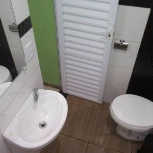 La salle de bains est pourvue d'un lavabo blanc et de toilettes. dans l'établissement Pousada Aconchego, à Mateiros
