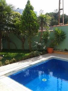 a blue swimming pool in a yard with palm trees at Konak Hotel Tuzla in Tuzla