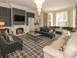 a living room with leather furniture and a fireplace at Maes Elwy in St Asaph