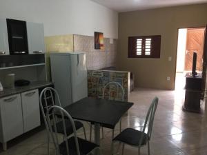 una cucina con tavolo, sedie e frigorifero di Residencial Sibaúma a Pipa