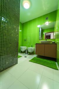a green bathroom with two sinks and a mirror at Casas do Prior in Trevões