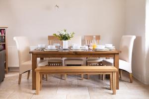 een eettafel met witte stoelen en een houten tafel en stoelen bij Finest Retreats - Berry Cottage - 4 Bedroom, Pet-Friendly Cottage Sleeping 8 in Eglwyswrw